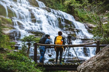 Çiftler şelalenin güzel fotoğraflarını çekmek için rahatça seyahat ederler. Kışın. Tayland 'daki Mae ya Chiangmai şelalesinde. Seyahat doğası. yaz