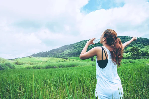 Asyalı kadınlar tatilde rahatlarlar. Yeşil bir çayırda Su İç.