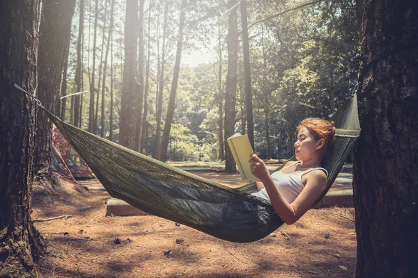 Kadınlar uyurken kitap okuyor. Hamakta. Parktaki doğal atmosferde