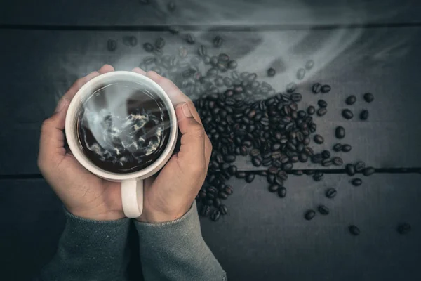 En kvinnas hand håller ett kaffeglas på ett träbord. — Stockfoto