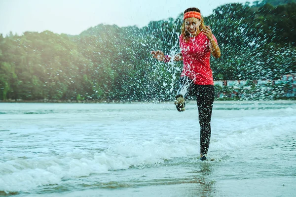 Asiatico donna jogging allenamento sulla spiaggia al mattino. Rilassati con la spiaggia. divertente e felice di giocare, saltare, calciare il mare. in estate — Foto Stock