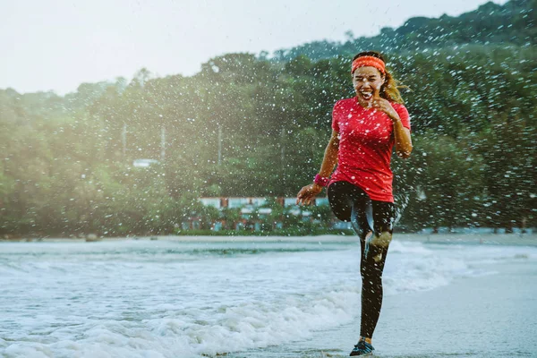 Asiatico donna jogging allenamento sulla spiaggia al mattino. Rilassati con la spiaggia. divertente e felice di giocare, saltare, calciare il mare. in estate — Foto Stock