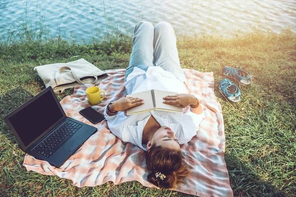 Les femmes assis un relax travailler avec un cahier et couché lire un livre pendant une détente dans le parc. pendant les vacances. été — Photo