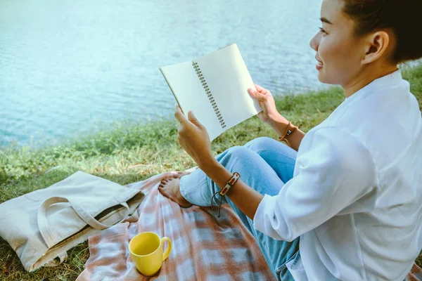아시아 여성 이 공원에 앉아 쉬고 있습니다. 휴일에 앉아서 책을 읽고 커피를 마시며. — 스톡 사진