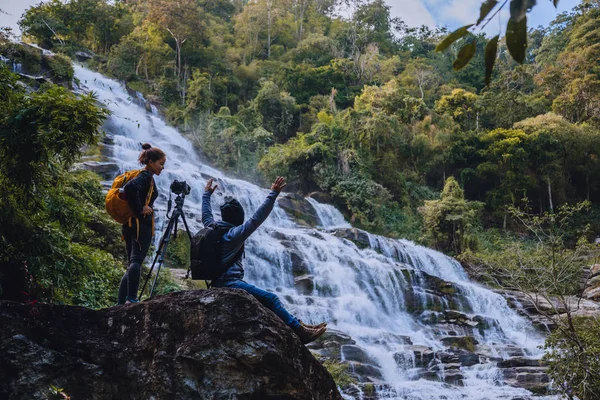 Pareja asiática viajar naturaleza. Relájate. Paisajes de pie Natural Touch Stand para ver hermosas cascadas mae ya en Chiangmai en Tailandia — Foto de Stock