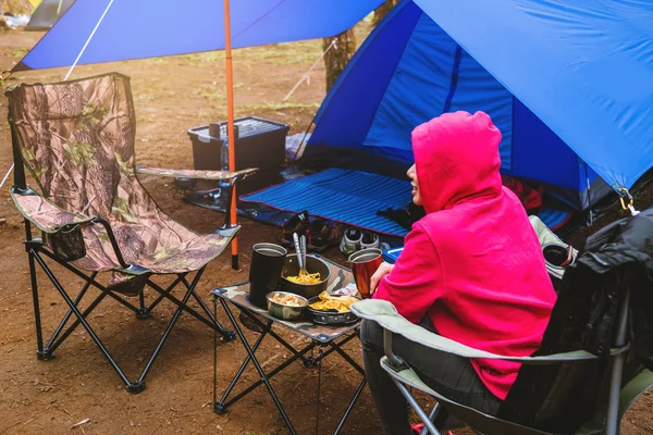 Mulheres Turismo de natureza, acampando no meio da floresta de pinheiros. Sentado e comer comida na frente da tenda — Fotografia de Stock