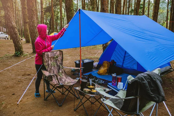 Vrouwen Natuur toerisme, kamperen in het midden van het dennenbos. Het verstellen en trekken van het tenttouw. — Stockfoto