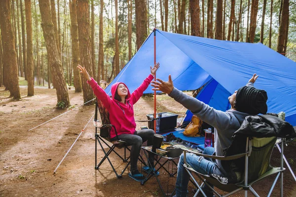 Jovem casal asiático de feliz apreciando Acampar na floresta de pinheiros Sente-se e coma comida na página Camping no meio da natureza . — Fotografia de Stock