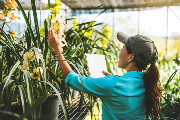 Asiatisk kvinna resa slappna orkidé utbildning Skriv anteckningar i Orchid Garden, bakgrund orkidé. — Stockfoto