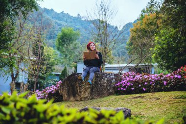 kadın çiçek bahçesinde doğa seyahat. doi Inthanon doğanın ortasında kayalar üzerinde oturan ve kitap okuma dinlenmek.