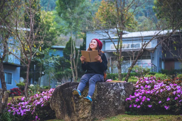 Mujer viajar naturaleza en el jardín de flores. relajarse sentado en las rocas y la lectura de libros En medio de la naturaleza en doi Inthanon . — Foto de Stock