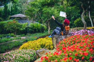 kadın çiçek bahçesinde doğa seyahat. kayalar üzerinde oturan ve milli park doi Inthanon doğanın ortasında kitap okuma dinlenmek.