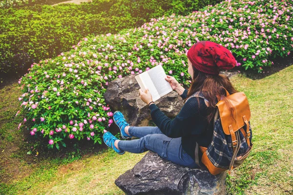 Frau reist Natur im Blumengarten. Entspannen Sie sich auf Felsen und lesen Sie Bücher inmitten der Natur im Nationalpark doi inthanon. — Stockfoto