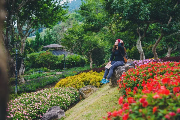 Frau reist Natur im Blumengarten. Entspannen Sie sich auf Felsen und lesen Sie Bücher inmitten der Natur im Nationalpark doi inthanon. — Stockfoto