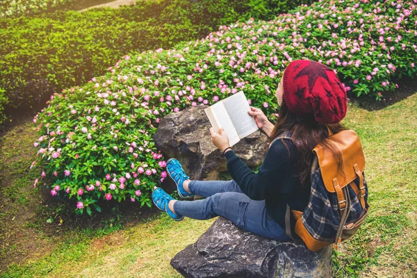 Mulher viajar natureza no jardim de flores. relaxar sentado em rochas e ler livros No meio da natureza no parque nacional doi Inthanon . — Fotografia de Stock