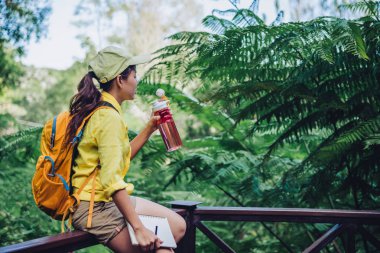 Genç kadın ormanın doğasını araştırmak ve kayıt etmek için seyahat ediyor. Oturuyor, dinleniyor ve su içiyor..