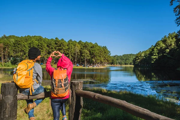 Pár cestovatelů s batohem stojící na vrcholu vyhlídkové přírody krásné, Užijte si východ slunce na zamlženém povrchu jezera, Mladí muži a asijské přítelkyně cestovat přírodu na horském Pang Ung parku v Thajsku. — Stock fotografie