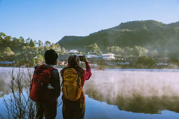 Een Aziatisch stel dat 's morgens de mist op het meer ziet opkomen. Travel Ban Rak Thais dorp, Mae Hong Son in Thailand. Neem een foto van het meer — Stockfoto