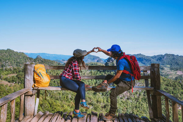 Asian couple Tourists with backpacks Happy to travel She raised her hand to make a heart shape and enjoy the natural scenery on the mountain.