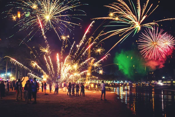 Fyrverkerier med siluetter av människor i ett semesterevenemang.Nyårsfyrverkerier på stranden. Resenärer och människor firar nyårsdagen på Kamala Beach Phuket, Thailand. — Stockfoto