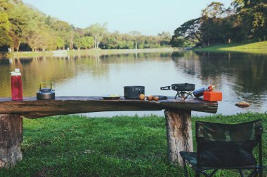 Tencerenin arka planı ve masa tahtasına konan benzin pikniği. Kamp, piknik, yemek, göl kenarında yemek..