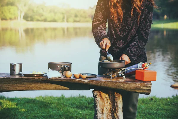 Femme touriste naturelle, elle prend le petit déjeuner, mange de la nourriture. Voyage camping au bord du lac, Voyage nature . — Photo