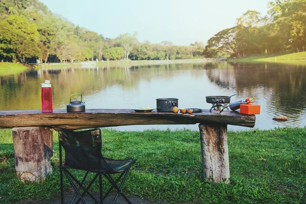 Lo sfondo del picnic pentola e gas che viene posto sul tavolo in legno. Campeggio, picnic, cucina, mangiare in riva al lago . — Foto Stock