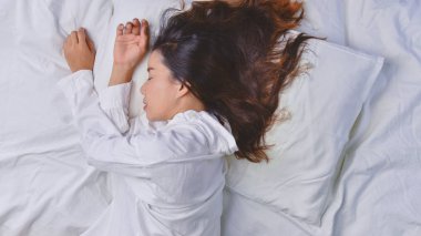 Yatakta Uyuyan Genç Kadın. Yatakta rahat uyuyan genç bir kadın manzarası. Uyuyor, rahatlıyor, gülümsüyor güzel bayan yatakta yatıyor..