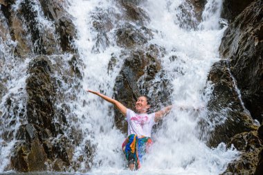 Tatilde şelaleyi gezen kız. Şelaleyi mutlu bir şekilde çalan kız. Doğayı gezmek, rahatlamak, Tayland 'ı gezmek. Huai Toh Şelalesi Krabi 'de..
