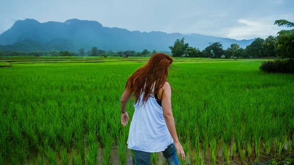 Asyalı kadınlar tatillerde rahatça seyahat eder. Kız mutlu bir şekilde gülümsedi ve yağan yağmurun tadını çıkardı. Ülkelerde seyahat, yeşil pirinç tarlaları, Tayland seyahatleri..