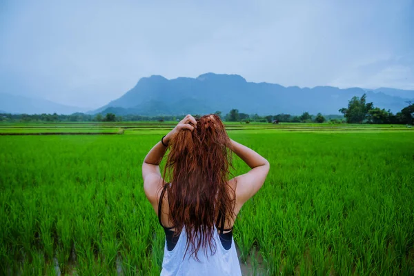 Asiatische Frauen reisen entspannt in den Urlaub. Das Mädchen lächelte glücklich und genoss den Regen, der fiel. Reisen in ländliche Gegenden, grüne Reisfelder, Reisen nach Thailand. — Stockfoto