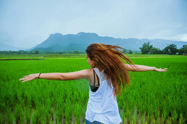 Asiatische Frauen reisen entspannt in den Urlaub. Das Mädchen lächelte glücklich und genoss den Regen, der fiel. Reisen in ländliche Gegenden, grüne Reisfelder, Reisen nach Thailand. — Stockfoto