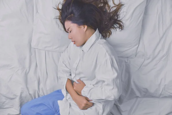 Mujer joven durmiendo en la cama. Pero el insomnio causado por dolor abdominal severo. Insomnio causado, Personas Duermen, Ojos cerrados, Enfermedad, Dolor, Enfermedad mortal, Enfermedad, Enfermedad . — Foto de Stock
