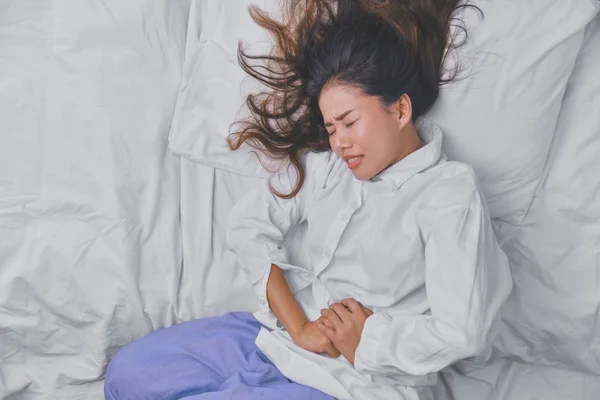 Mujer joven durmiendo en la cama. Pero el insomnio causado por dolor abdominal severo. Insomnio causado, Personas Duermen, Ojos cerrados, Enfermedad, Dolor, Enfermedad mortal, Enfermedad, Enfermedad . — Foto de Stock