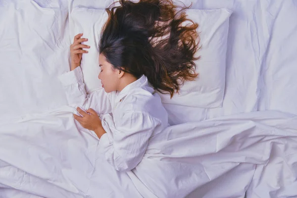 Jovem mulher dormindo na cama. Visão superior da jovem deitada dormindo bem na cama. dormir relaxar, jovem sorridente bonita senhora encontra-se na cama . — Fotografia de Stock