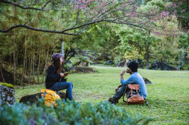Oturan Asyalı turistler ahşap platformda erişte yiyorlar ve Ban Jabo, Mae Hong Son, Tayland 'daki güzel doğa dağlarının manzarasına bakıyorlar..