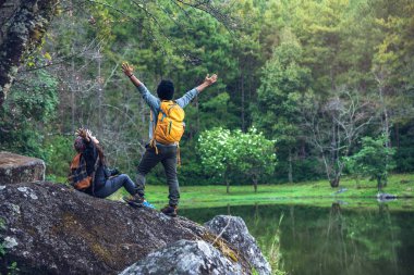 Kayaların üzerinde oturup doğa ve çiçeklerin fotoğraflarını çeken bir çift. Paphiopedilum Orkide Koruma Merkezi 'nde.