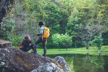 Kayaların üzerinde oturup doğa ve çiçeklerin fotoğraflarını çeken bir çift. Paphiopedilum Orkide Koruma Merkezi 'nde.