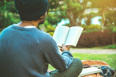 Genç adam parkta bir kitap okuyordu. Doğal ağaçların ve güzel çiçek bahçelerinin arasında