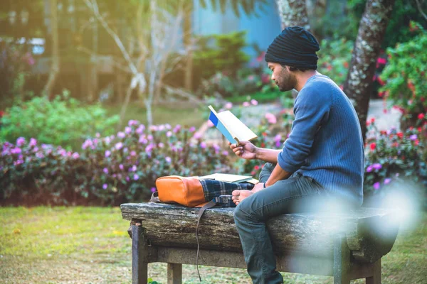 그 젊은이는 그 공원에서 책을 읽고 있었다. 자연 나무와 아름다운 화원 사이에 — 스톡 사진