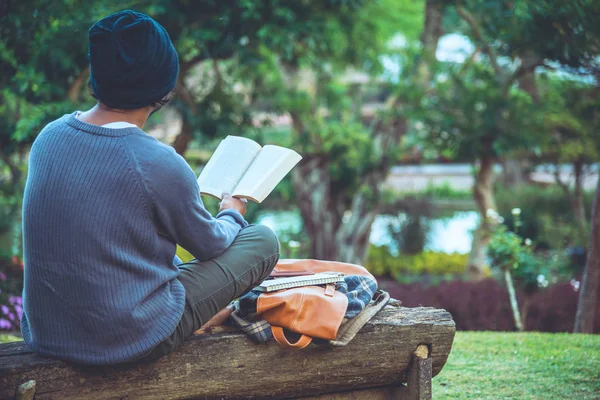 Молодой человек читал книгу в парке. Среди природных деревьев и красивого цветочного сада — стоковое фото