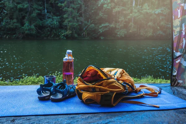 Reis de natuur. Reizen ontspannen. Rugzak en schoenen mobiele telefoon met een traveler.sun geplaatst voor de tent camping. Achtergrond van de natuur van het bergmeer. — Stockfoto