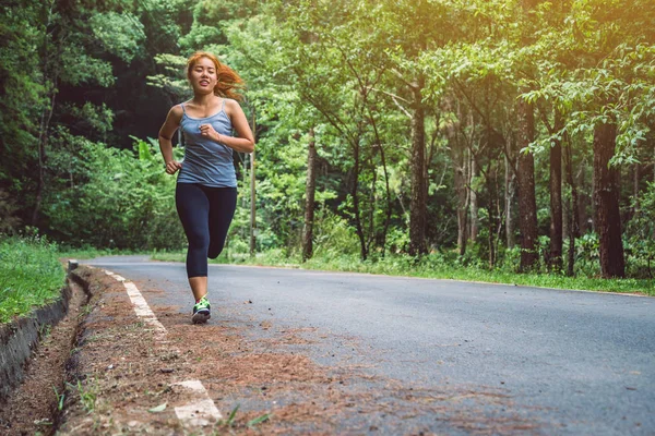 Le donne si allenano per strada. Parco naturale. Ragazza che sta sollevando le gambe per esercitare. esercizio, corsa, ragazza che corre jogging . — Foto Stock