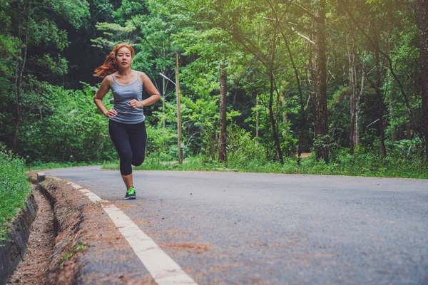 Le donne si allenano per strada. Parco naturale. Ragazza che sta sollevando le gambe per esercitare. esercizio, corsa, ragazza che corre jogging . — Foto Stock