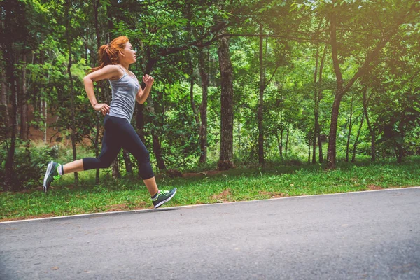 Le donne si allenano per strada. Parco naturale. Ragazza che sta sollevando le gambe per esercitare. esercizio, corsa, ragazza che corre jogging . — Foto Stock