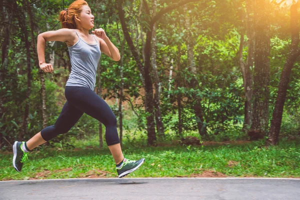 Le donne si allenano per strada. Parco naturale. Ragazza che sta sollevando le gambe per esercitare. esercizio, corsa, ragazza che corre jogging . — Foto Stock