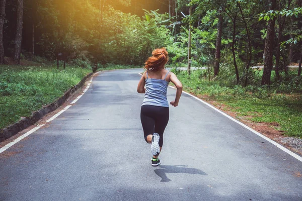 Le donne si allenano per strada. Parco naturale. Ragazza che sta sollevando le gambe per esercitare. esercizio, corsa, ragazza che corre jogging . — Foto Stock