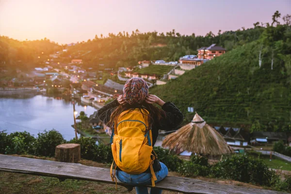 Jonge vrouw met rugzak genieten van zonsondergang op de top van de berg. Toeristen staan in een thee plantage kijkend naar de prachtige berg zon bij Ban Rak Thai dorp. — Stockfoto