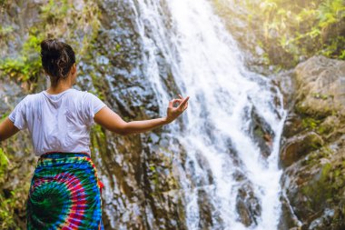 Asyalı kadınlar tatilde dinlenir. Yoga yap. Moutain Şelalesi 'nde yoga yapsak olur mu? Egzersiz, sağlık, seyahat, rahatlama. Tayland seyahati. (Huai Toh şelalesi )