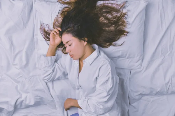 Mujer joven durmiendo en la cama. Vista superior de la mujer joven acostada durmiendo bien en la cama. dormir relajarse, joven sonriente hermosa dama se encuentra en la cama. relajante, durmiendo . — Foto de Stock